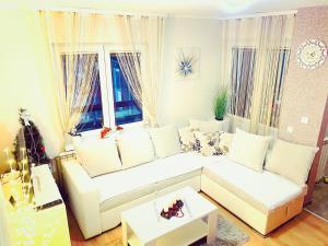 a living room with a white couch and two windows at Apartman Sanja Divčibare in Divčibare