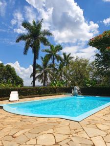 uma piscina azul com palmeiras ao fundo em Linda Chácara - Águas de São Pedro - Próximo ao Parque Thermas em Águas de São Pedro