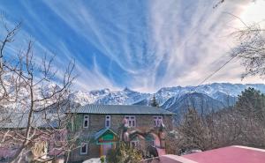 un edificio con montañas cubiertas de nieve en el fondo en Farmvilla Homestay, en Kalpa 22 fotos más
