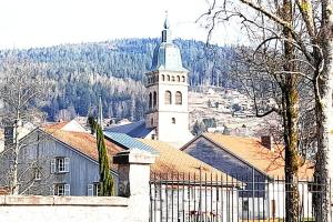 une église avec une cloche devant un bâtiment dans l'établissement Le 1A, Charmant Appartement au Cœur de la Ville, à Gérardmer 1 autre photo