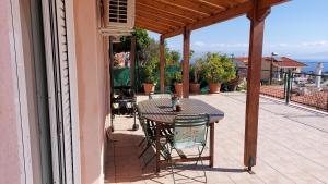 um pátio com uma mesa e cadeiras numa varanda em Airport Friendly House 1 em Artemida