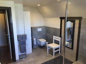 een badkamer met een toilet en een stoel. bij B&B Carisma in Lochristi