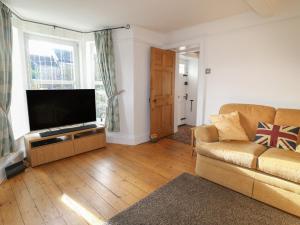 a living room with a couch and a flat screen tv at Lavender Cottage in Belper
