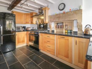 a large kitchen with wooden cabinets and a clock on the wall at Lavender Cottage in Belper
