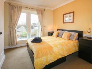 a bedroom with a bed with a yellow comforter and a window at Lavender Cottage in Belper