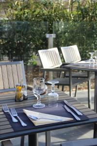 an outdoor table with glasses and silverware on it at Kyriad Saint Quentin en Yvelines - Montigny in Montigny-le-Bretonneux