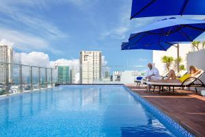 a couple sitting on chairs next to a swimming pool on a building at CN Palace Boutique Hotel & Spa in Danang