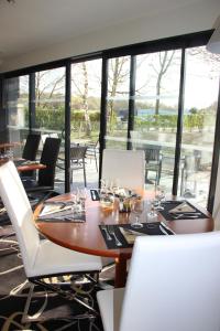 uma sala de jantar com mesa, cadeiras e janelas em Kyriad Saint Quentin en Yvelines - Montigny em Montigny-le-Bretonneux