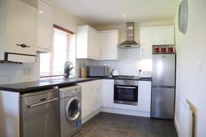 a kitchen with white cabinets and a washer and dryer at Letting Serviced Apartments - Sheppards Yard, Hemel Hempstead Old Town in Hemel Hempstead