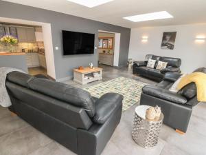 a living room with black leather furniture and a flat screen tv at Maes Llwyd in Brynteg