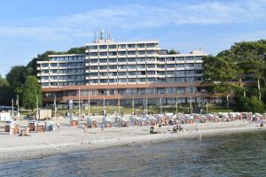 a hotel on the beach with people on the beach at fewo1846 Intermar - Kajuete Foerdeblick - familienfreundliches Studioapartment mit Balkon und Meerblick in Glücksburg