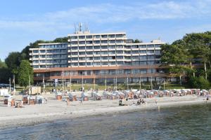 a hotel on the beach with people on the beach at fewo1846 - Intermar Lina K - Luxuriöses Apartment im 6 OG mit Balkon und Meerblick in Glücksburg