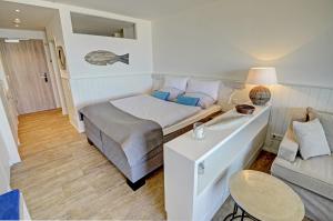 um pequeno quarto com uma cama e um sofá em fewo1846 Intermar - At the beach - luxuriöses Studioapartment mit Balkon und Meerblick im 2 OG em Glücksburg