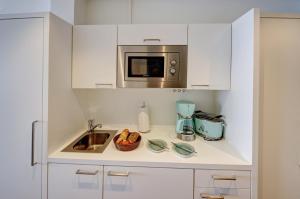 a kitchen with a sink and a microwave at fewo1846 Intermar - Rooftop - Luxuriöses Studioapartment mit Balkon und Meerblick im 7 OG in Glücksburg