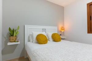 Dormitorio blanco con almohadas amarillas en una cama en Eclipse, en Puerto del Rosario