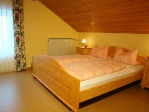 a bedroom with a large wooden bed with pink pillows at Gästehaus Baumgartner in Bad Birnbach