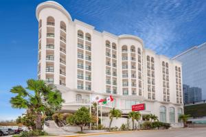 un gran edificio blanco con palmeras delante en Ramada Plaza by Wyndham Veracruz Boca del Rio en Veracruz