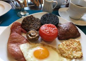 a plate of breakfast food with eggs bacon and tomatoes at An Cuan Bed & Breakfast in Bowmore