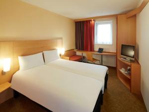 een hotelkamer met een groot wit bed en een televisie bij ibis Reading Centre in Reading