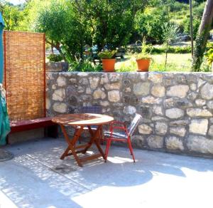 a table and a chair next to a stone wall at Apartment Lepur Slano in Slano