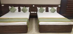 two twin beds in a room with sidx at Hotel Grand Gaayatris in Chennai