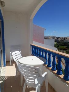 een witte tafel en stoelen op een balkon met uitzicht bij cantinho do mar in Albufeira