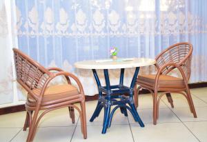 a table and two chairs and a table with a vase on it at Vienna Woods Hotel Nakuru in Nakuru