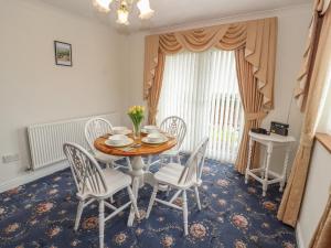 a dining room with a wooden table and chairs at Enlli in Holywell