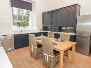 cocina con mesa de madera con sillas y nevera en 1 Tyn Y Caeau Apartment, en Menai Bridge