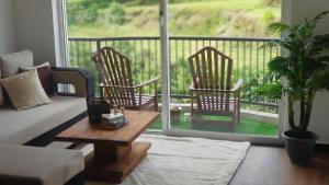 ein Wohnzimmer mit einem Sofa und 2 Stühlen auf einem Balkon in der Unterkunft Lake Infinity Luxury Condos in Nuwara Eliya