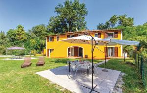 ein gelbes Haus mit einem Tisch und einem Regenschirm in der Unterkunft Holiday Pianamaggio in Carrara