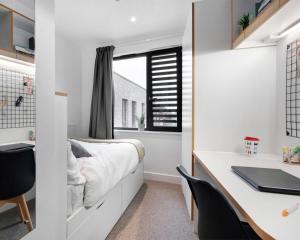 a bedroom with a bed and a desk with a laptop at Zeni Ensuite, in Colchester in Colchester