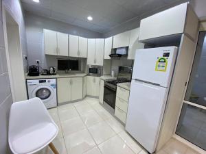 a kitchen with white cabinets and a white refrigerator at شقق شاطئ النخيل in Umm Lajj