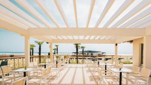 a patio with tables and chairs and the beach at Azul Beach Resort Montenegro by Karisma - All Inclusive in Ulcinj