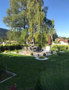 eine Liegewiese mit Stühlen, einem Tisch und einem Baum in der Unterkunft Appartement Wonder in Couvet