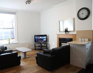 a living room with a couch and a clock on the wall at Letting Serviced Apartments - Guards View, Windsor in Windsor