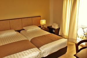 a bedroom with two beds and a lamp and a window at Rea Hotel in Heraklio +28 photos