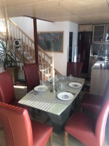 a dining room table with red chairs and a table with plates at Ferienwohnung Amperweg Fürstenfeldbruck in Fürstenfeldbruck