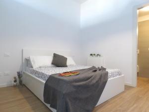 a white bedroom with a bed with a blanket on it at Lazzaretto Apartments in Bologna