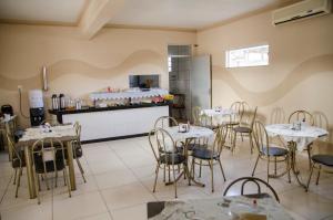 a restaurant with tables and chairs and a kitchen at Hotel Shalom Santa Maria do Pará in Santa Maria do Pará