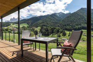 a deck with a table and chairs and mountains at Peterwieshof in Funes