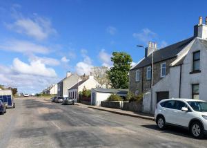 une rue avec des maisons et des voitures garées dans la rue dans l'établissement An Cuan Bed & Breakfast, à Bowmore