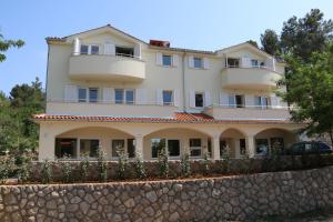 a large white house with a stone wall at Apartments Sucic Iva i Tea in Soline