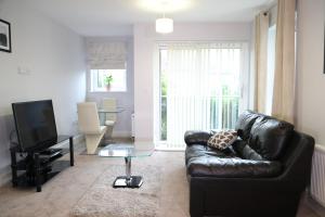 uma sala de estar com um sofá de couro preto e uma televisão em Letting Serviced Apartments - Central St Albans em Saint Albans
