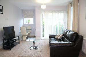 ein Wohnzimmer mit einem schwarzen Ledersofa und einem TV in der Unterkunft Letting Serviced Apartments - Central St Albans in St Albans