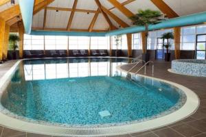 een groot zwembad met blauw water in een gebouw bij Beach Chalet Bad Hoophuizen VU43 in Hulshorst