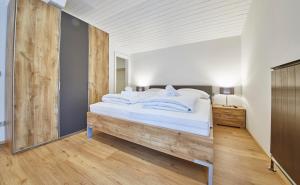 um quarto com uma cama grande e lençóis brancos em Appartements Haus Alexander em Saalbach-Hinterglemm