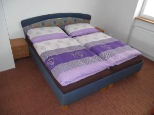 uma cama com lençóis e almofadas roxos e brancos em Penzion Apartmány Zlín em Zlín