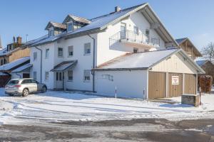 una casa blanca con un coche aparcado delante de ella en Ferienwohnung Altötting, en Unterneukirchen