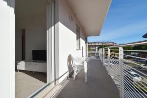 a balcony with a white chair and a television at Residence Al Molo - Agenzia Cocal in Caorle